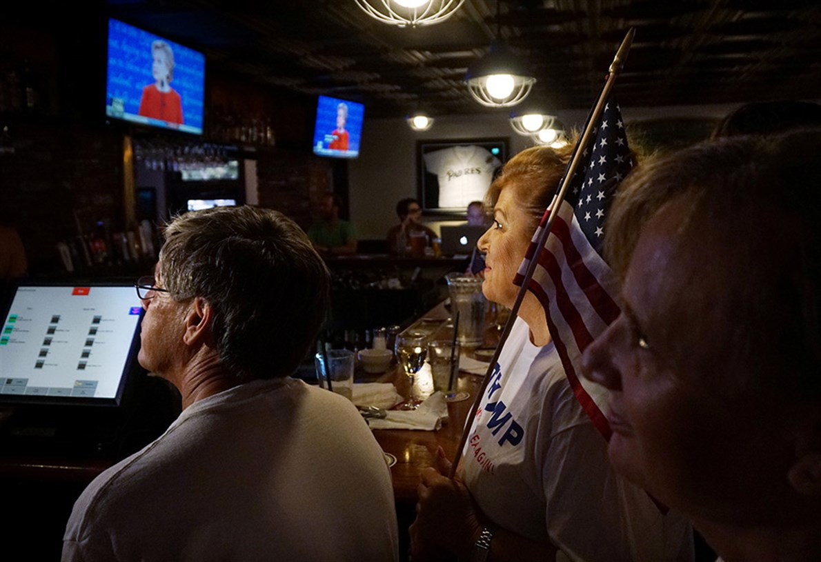 Varias personas siguen el debate en un bar de San Diego, California.