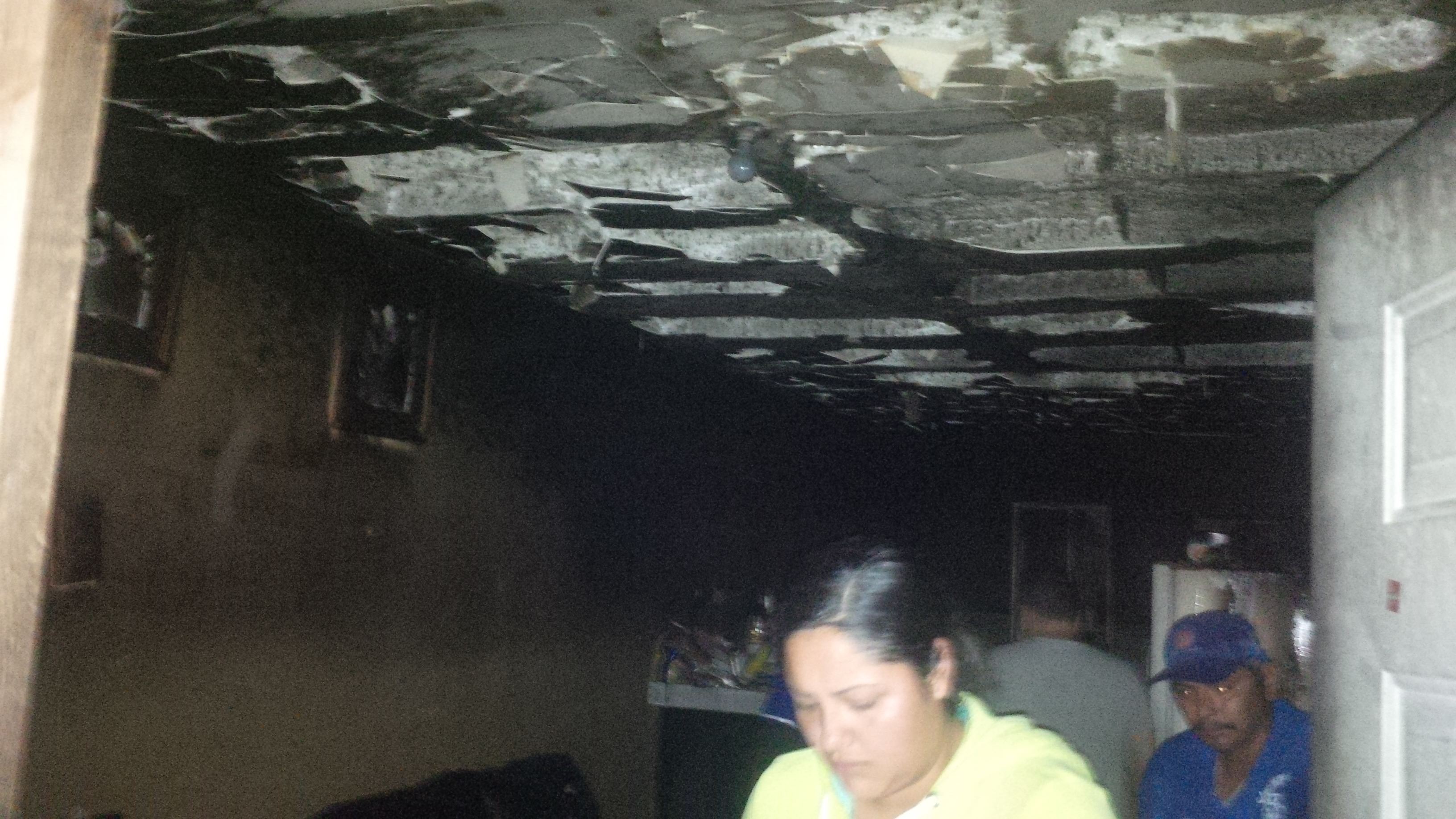 AFECTADA. La afectada con el incendio, Rita Martínez Paéz, muestra al personal de Protección Civil las condiciones en las que quedó el techo y el resto de su vivienda, luego del incendio.