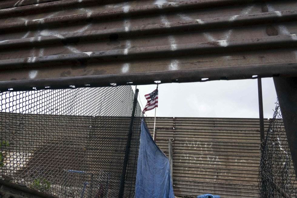 Una bandera estadounidense ondea en la frontera entre Estados Unidos y México a la altura de Tijuana, Baja California. Si se cumple el ofrecimiento del INM, el tamaño de la caravana se reducirá pero poco, según el activista, porque solo algunos viajan con