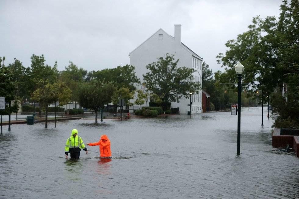 Dos vecinos cruzan una calle inundada de una zona residencial de New Bern (Carolina del Norte), el 13 de septiembre. CHIP SOMODEVILLA AFP