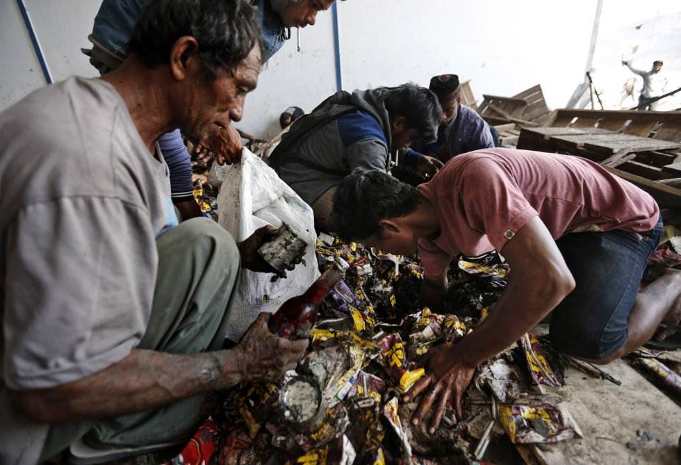 Hombres recolectan de una pila cualquier cosa comestible dentro de un almacén abandonado en Palu (Indonesia). DITA ALANGKARA AP