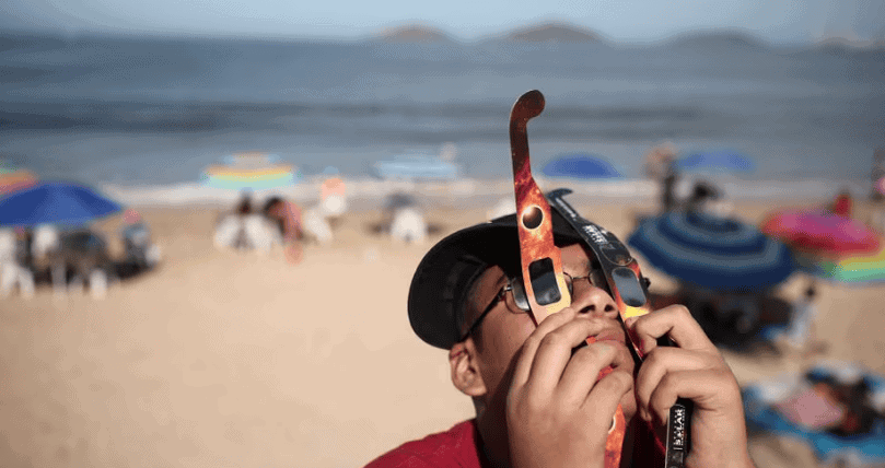 Un niño usa dos juegos de anteojos para ver el eclipse en Mazatlán.